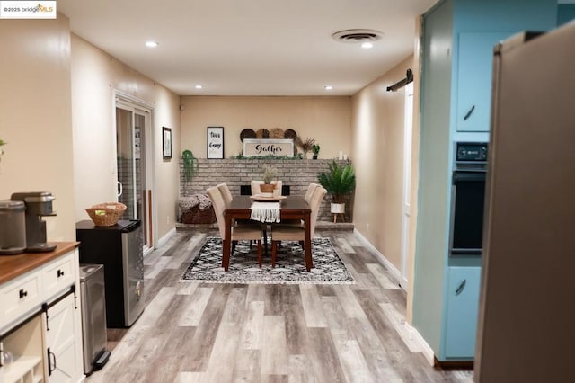 dining room with a barn door and light hardwood / wood-style floors