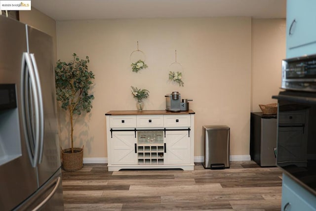 kitchen featuring wood-type flooring, stainless steel fridge, and oven