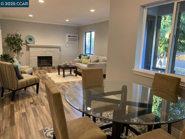 dining room with a fireplace, crown molding, wood-type flooring, and a wall unit AC