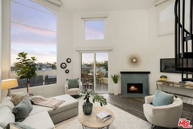 living room with hardwood / wood-style flooring, a fireplace, and a towering ceiling