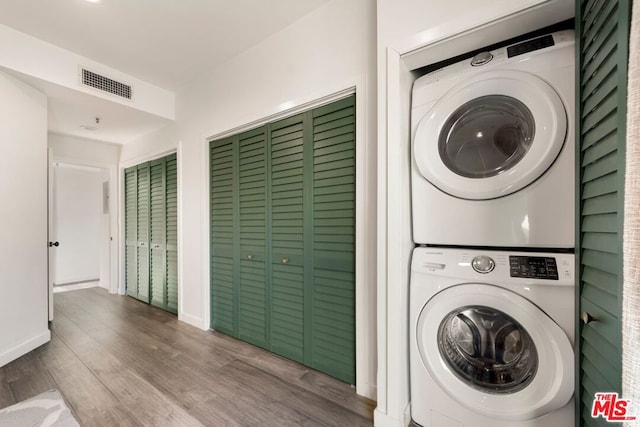 washroom with hardwood / wood-style flooring and stacked washer and dryer