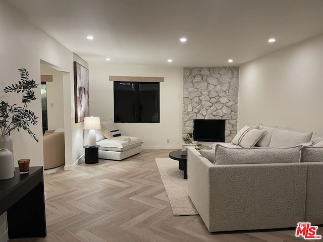 living room featuring a stone fireplace and light parquet floors