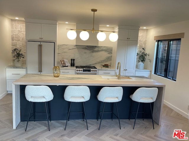 kitchen featuring sink, a breakfast bar, white cabinetry, high quality appliances, and decorative light fixtures