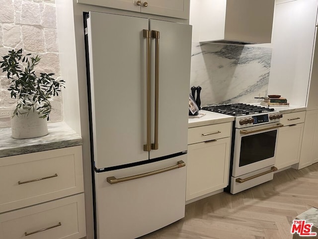 kitchen featuring high end fridge, tasteful backsplash, custom range hood, gas range oven, and light parquet floors