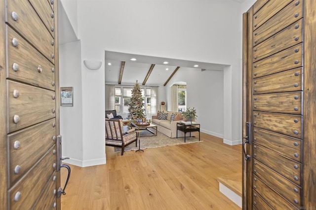 foyer with high vaulted ceiling, beam ceiling, and light hardwood / wood-style floors