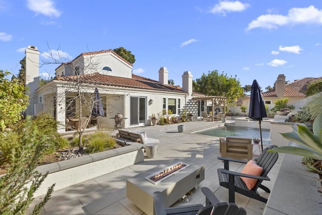 rear view of property featuring a patio and an outdoor fire pit