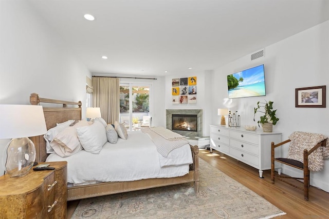 bedroom with hardwood / wood-style floors, a fireplace, and access to exterior