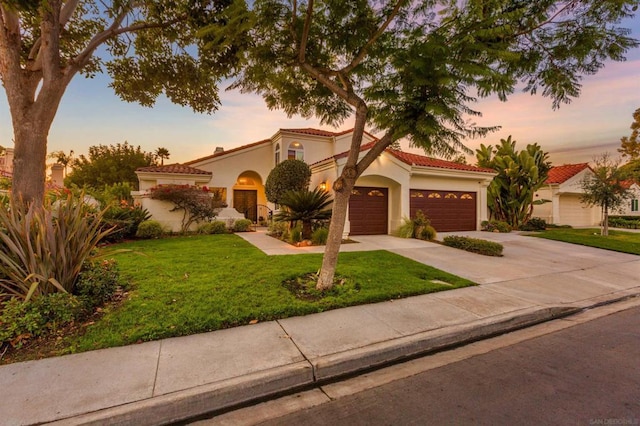 mediterranean / spanish-style home featuring a garage and a yard