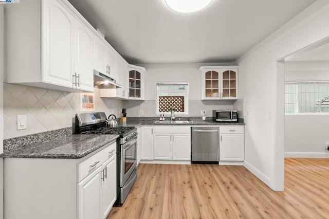 kitchen with sink, light wood-type flooring, white cabinets, and appliances with stainless steel finishes