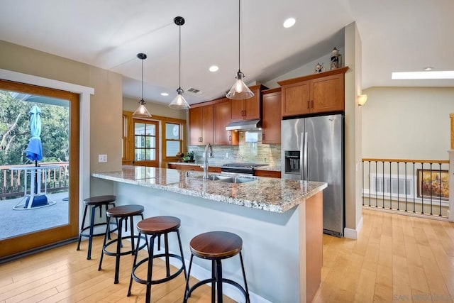 kitchen with sink, light stone counters, hanging light fixtures, appliances with stainless steel finishes, and kitchen peninsula