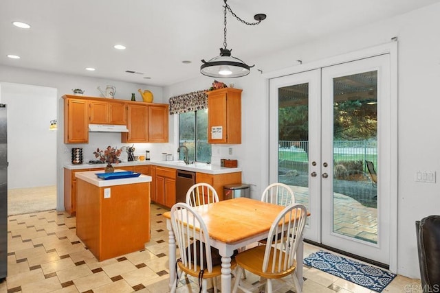 kitchen with light countertops, french doors, under cabinet range hood, and a kitchen island