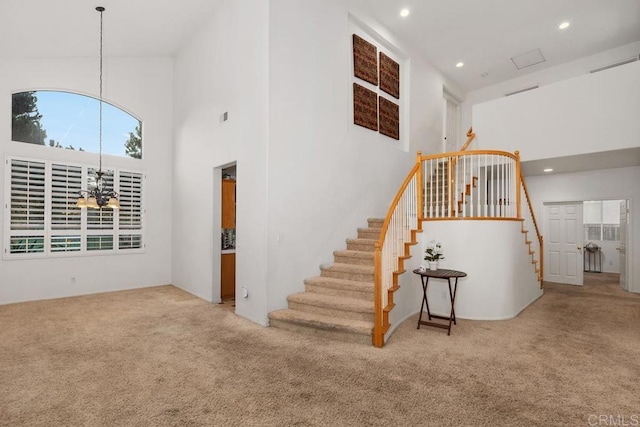 stairs featuring a notable chandelier, recessed lighting, carpet, and a towering ceiling