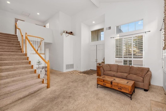 carpeted living room with beam ceiling, stairway, visible vents, and high vaulted ceiling