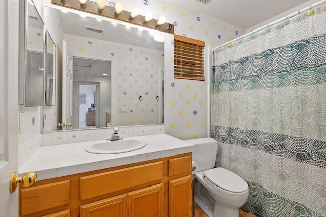 bathroom featuring visible vents, toilet, wallpapered walls, and vanity