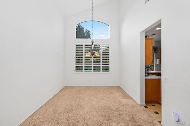 empty room featuring light carpet, a notable chandelier, and a towering ceiling