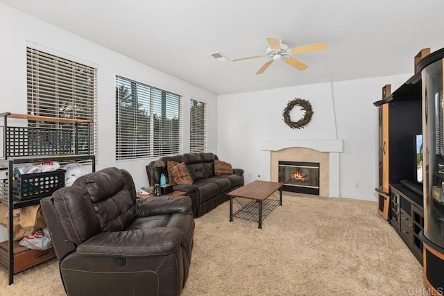 carpeted living area with visible vents, a ceiling fan, and a tile fireplace