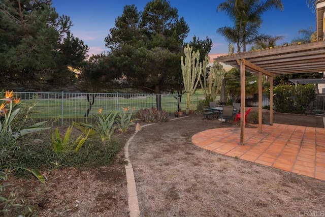 yard at dusk featuring a patio area, a pergola, and a fenced backyard