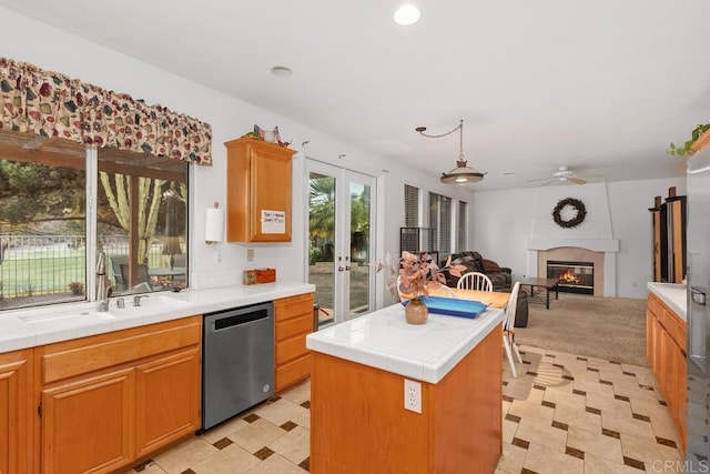 kitchen featuring open floor plan, tile countertops, dishwasher, and a sink