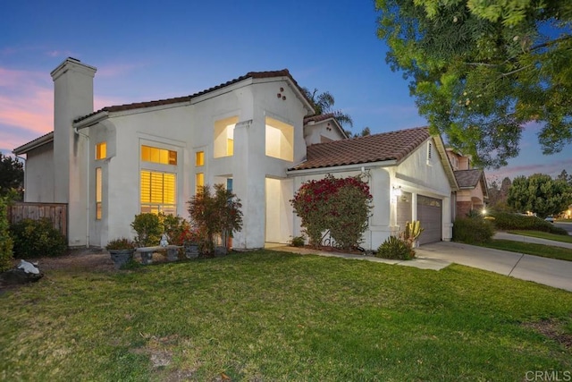 mediterranean / spanish house with a front yard, driveway, an attached garage, stucco siding, and a chimney