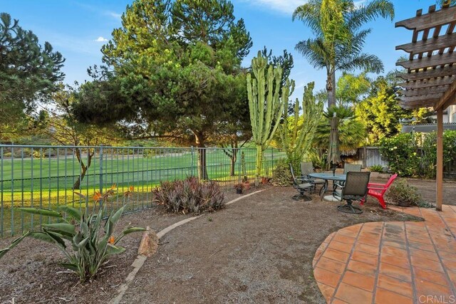 view of yard featuring a patio, outdoor dining area, and fence