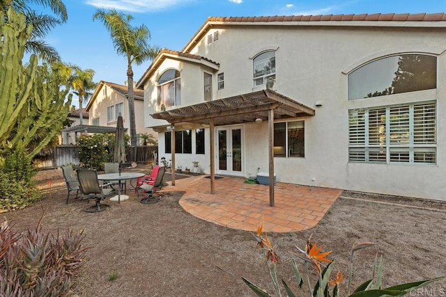 rear view of property with stucco siding, a pergola, a patio, fence, and french doors