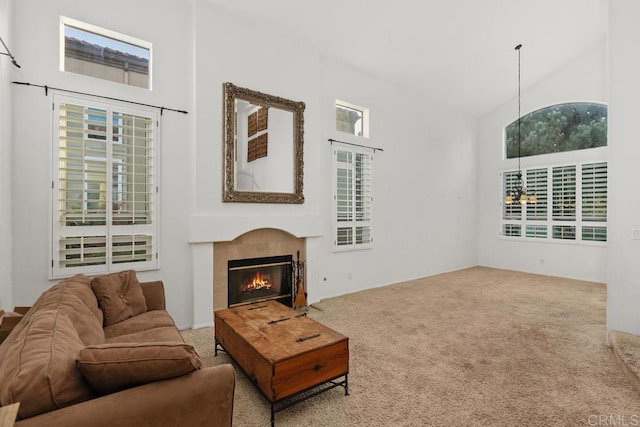 carpeted living room featuring high vaulted ceiling and a tile fireplace