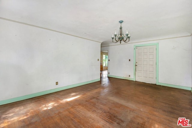 unfurnished living room featuring a notable chandelier and dark hardwood / wood-style flooring