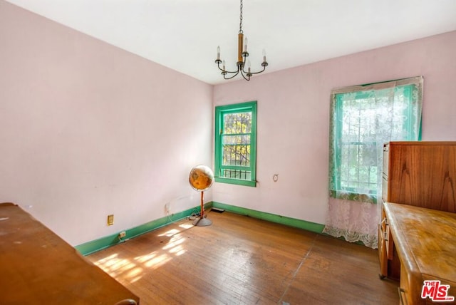 empty room with dark hardwood / wood-style flooring and a notable chandelier