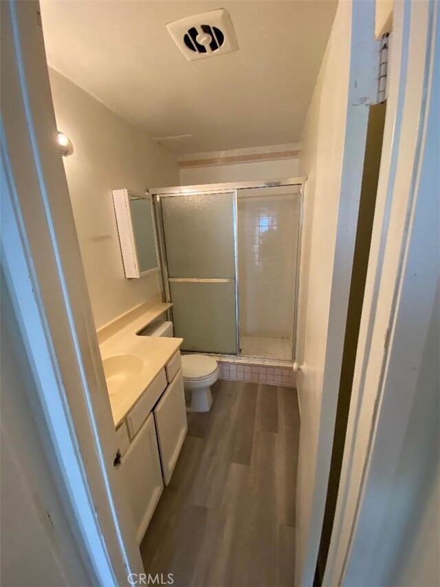 bathroom with vanity, hardwood / wood-style floors, an enclosed shower, and toilet