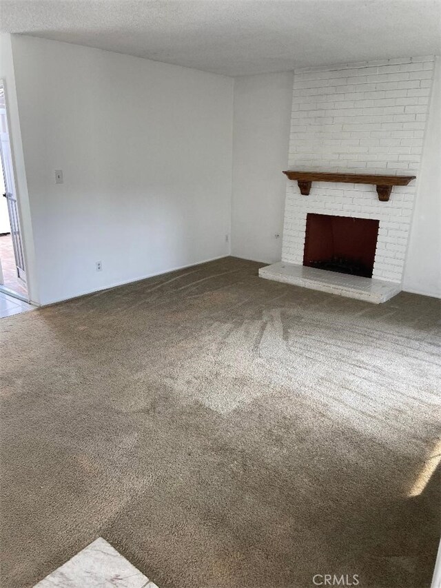 unfurnished living room with a fireplace, carpet, and a textured ceiling