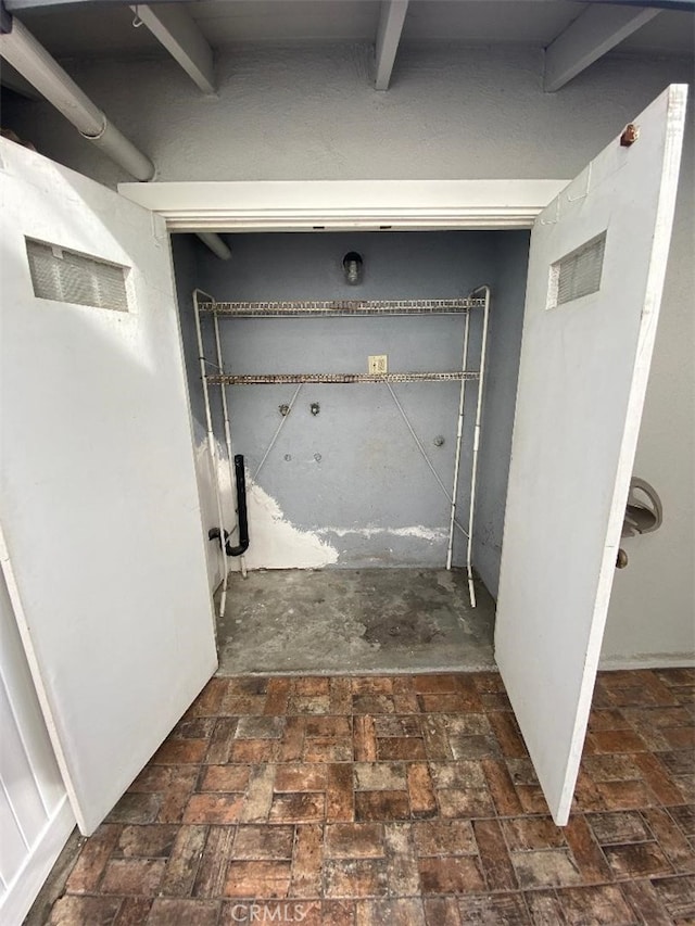 interior space featuring brick floor, visible vents, and beamed ceiling