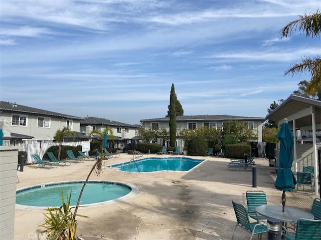 community pool featuring a residential view, fence, and a patio