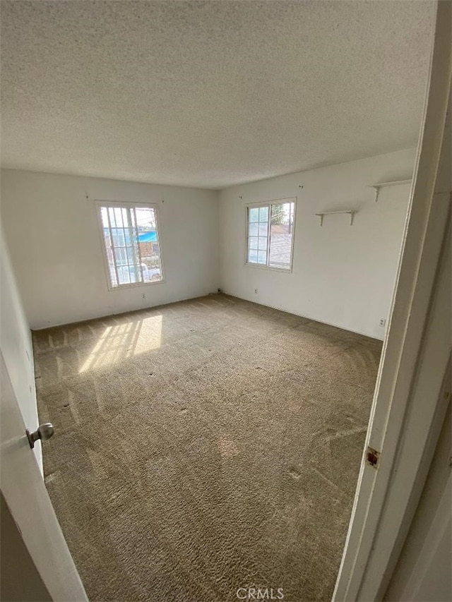 carpeted empty room with a textured ceiling