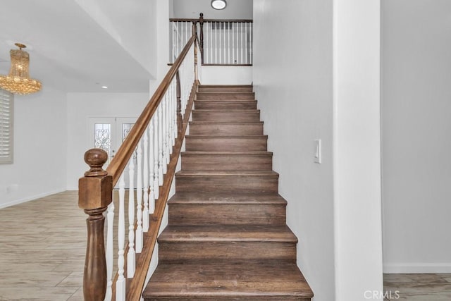 staircase with a notable chandelier and hardwood / wood-style flooring