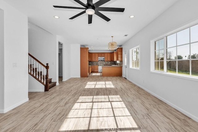 unfurnished living room featuring ceiling fan and light wood-type flooring