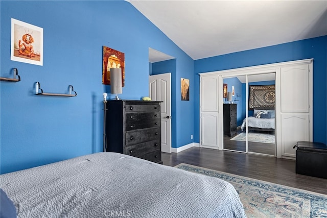 bedroom with lofted ceiling, dark hardwood / wood-style floors, and a closet