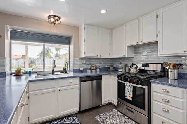 kitchen with sink, dark tile patterned floors, appliances with stainless steel finishes, tasteful backsplash, and white cabinets