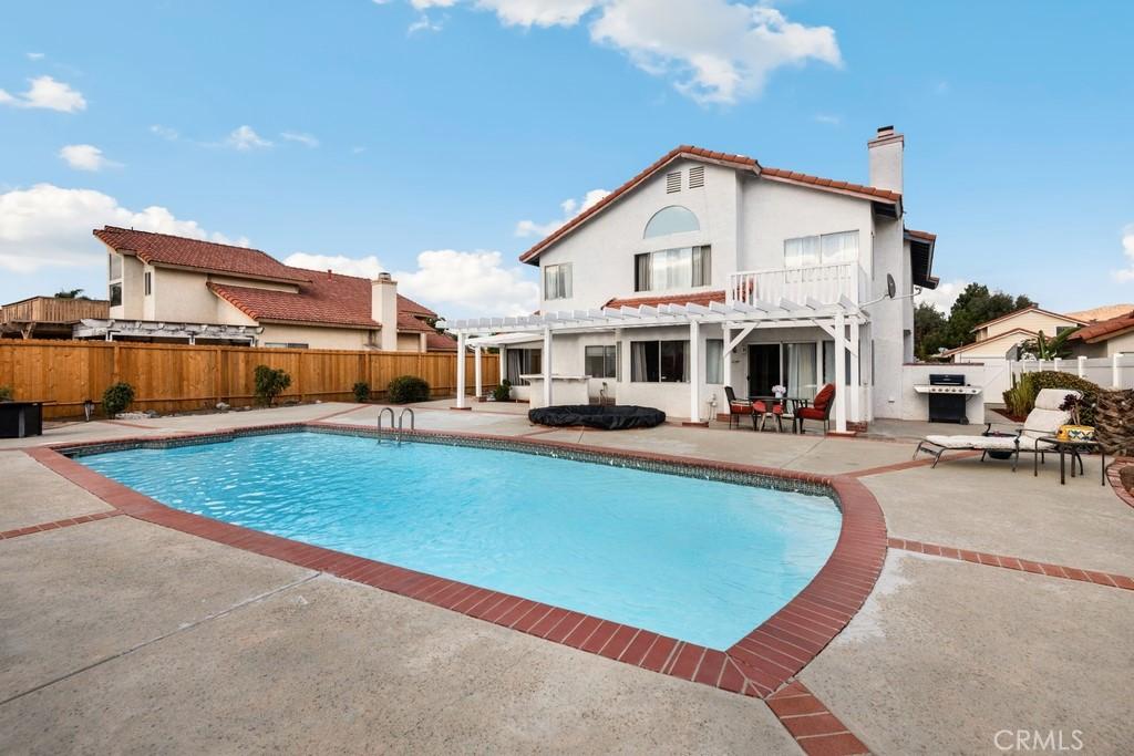 rear view of property with a fenced in pool, a patio area, and a pergola