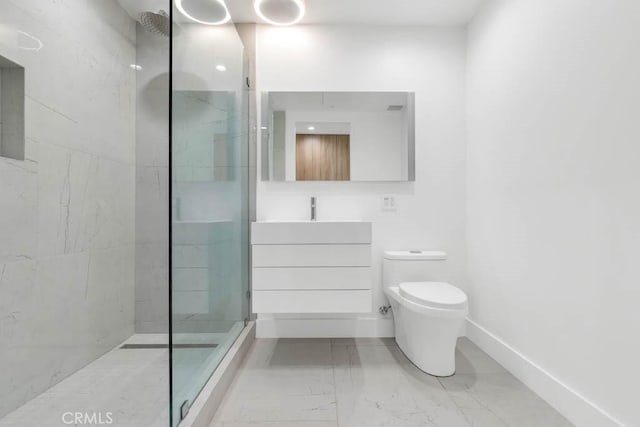 bathroom with vanity, tiled shower, and toilet