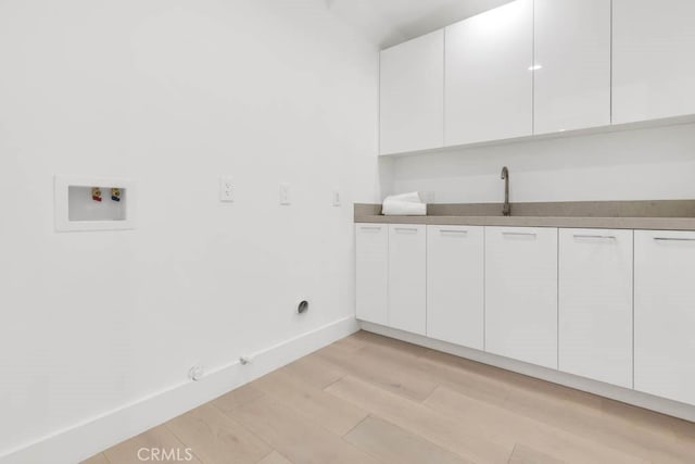 laundry area with sink, gas dryer hookup, cabinets, light hardwood / wood-style flooring, and hookup for a washing machine