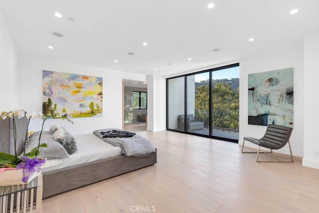 bedroom with expansive windows, connected bathroom, access to outside, and light wood-type flooring