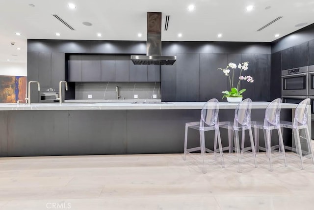 kitchen featuring island range hood, oven, a kitchen bar, and white gas cooktop