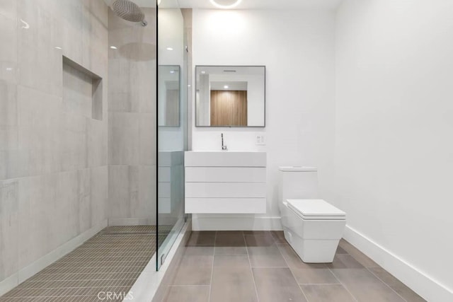 bathroom featuring vanity, tile patterned flooring, toilet, and a tile shower