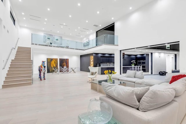 living room featuring a towering ceiling and light hardwood / wood-style floors