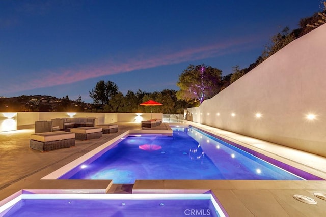 pool at dusk featuring a patio