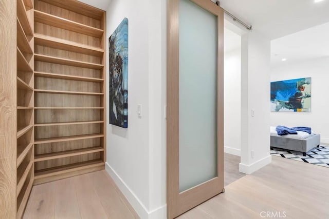 corridor featuring a barn door and light wood-type flooring