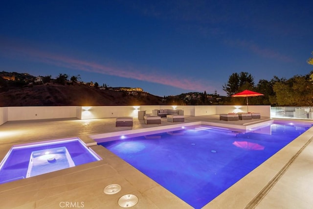 pool at dusk with an outdoor living space and an in ground hot tub