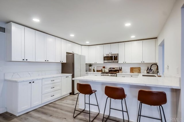 kitchen featuring sink, a breakfast bar area, white cabinets, and appliances with stainless steel finishes