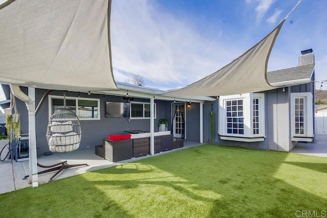 rear view of property with an outdoor living space, a patio, and a lawn