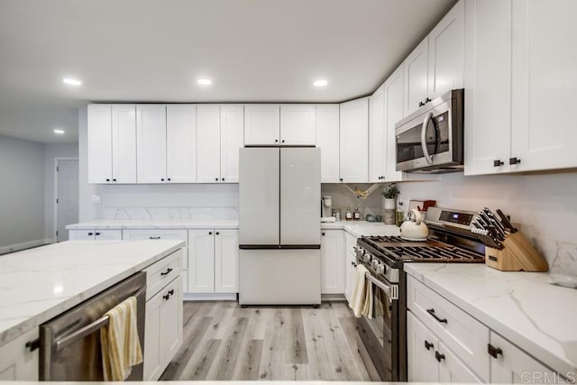 kitchen featuring white cabinetry, appliances with stainless steel finishes, light stone counters, and light hardwood / wood-style flooring